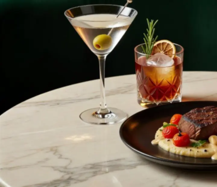 Contemporary dishes and cocktails styled on a dark table