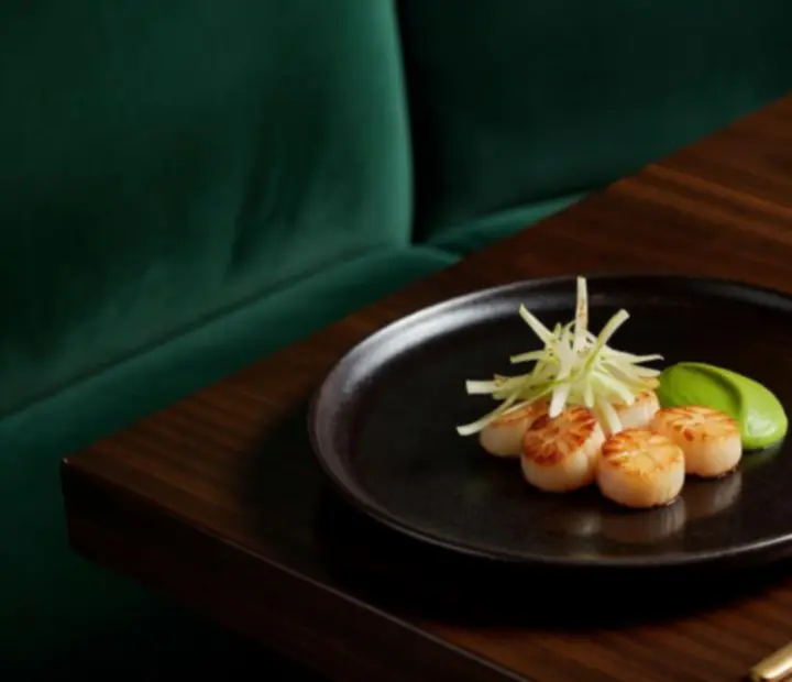 Fine dining dishes and signature cocktails styled on a dark timber table with warm light